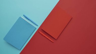 Mavi ve kırmızı arkaplan üzerine bir defter, okula geri dönmek, öğrenci aksesuarları, bir yazıt için boş alan, düz uzan