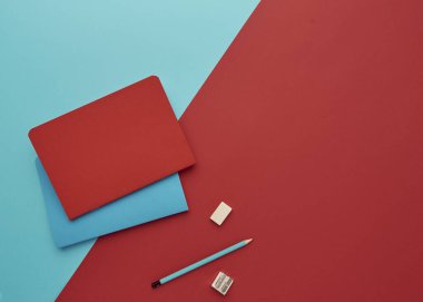 Mavi ve kırmızı arkaplan üzerine bir defter, okula geri dönmek, öğrenci aksesuarları, bir yazıt için boş alan, düz uzan