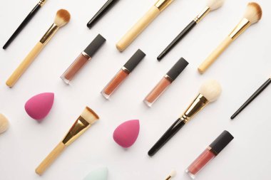 Makyaj fırçaları ve kozmetik ürünleri beyaz arka planda, düz yerde