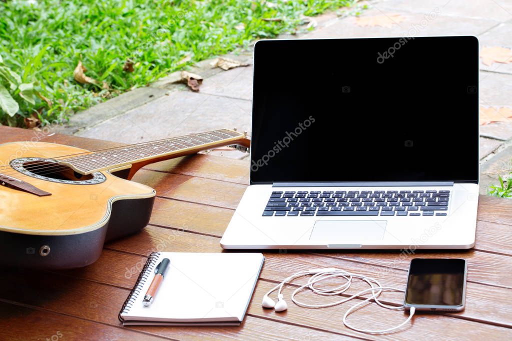 Workspace relaxing break inspiration outdoor with laptop mobile notebook acoustic guitar on wood ground