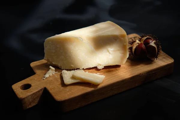 Cijfers van parmigiano reggiano of parmezaanse kaas op houten plaat op donkere ondergrond — Stockfoto