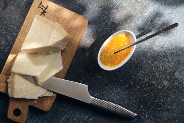 Cijfers van parmigiano reggiano of parmezaanse kaas op houten plaat op donkere ondergrond — Stockfoto