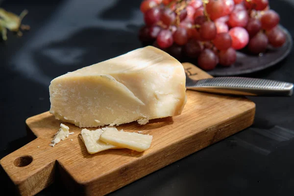 Cijfers van parmigiano reggiano of parmezaanse kaas op houten plaat op donkere ondergrond — Stockfoto