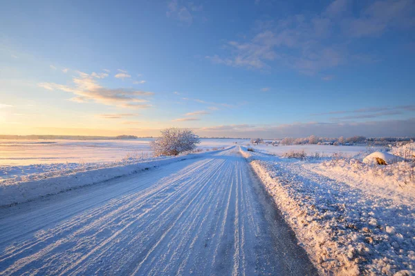 Estrada rural coberta de neve durante o pôr do sol de inverno — Fotografia de Stock