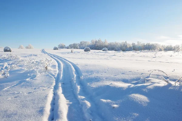 Tracks op een snowcovered veld met hooibalen — Stockfoto