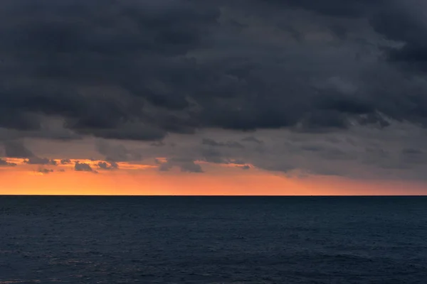 Ocean sunset with dramatic grey clouds — Stock Photo, Image