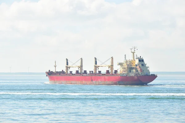 Красное грузовое судно, плывущее вдоль побережья — стоковое фото
