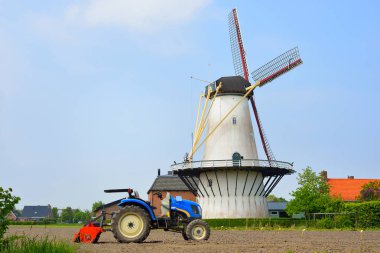 Bir yel değirmeni ve traktör ile klasik Hollandalı peyzaj 