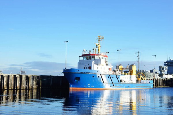 Пришвартованный буксир и военные корабли на пирсе 