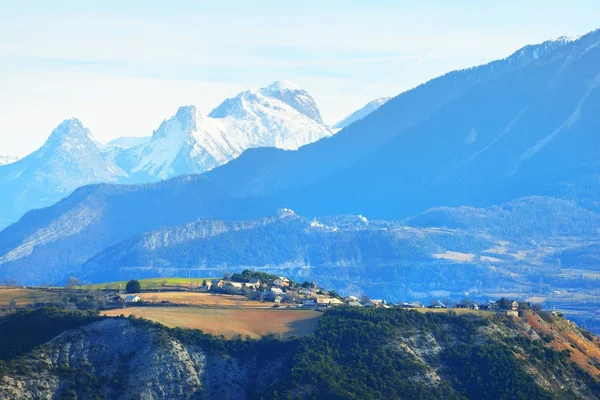 Alpes cumbres montañosas y un pueblo de montaña cerca del lago — Foto de Stock