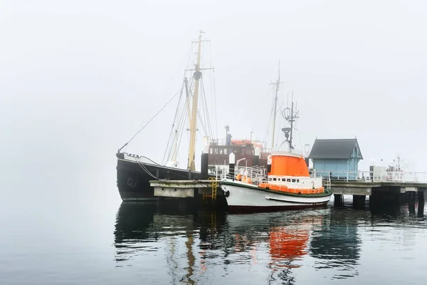 Une jetée avec de petits bateaux sous le brouillard — Photo