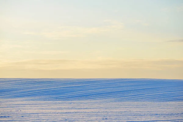 Campos agrícolas cobertos de neve durante o pôr do sol — Fotografia de Stock