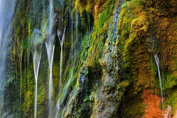 Waterfall on an orange cliff with green moss — Stock Photo, Image