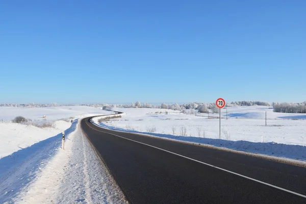 Downhill forest highway with sign in winter — Stock Photo, Image