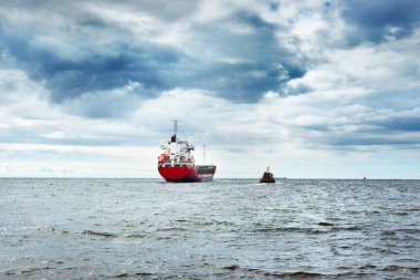 Genel kargo gemisi bir denizde bir römorkör yanındaki