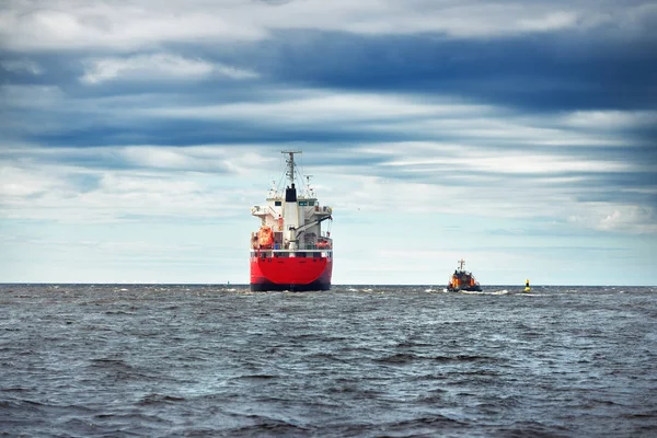 Algemene vrachtschip naast een sleepboot in een zee — Stockfoto