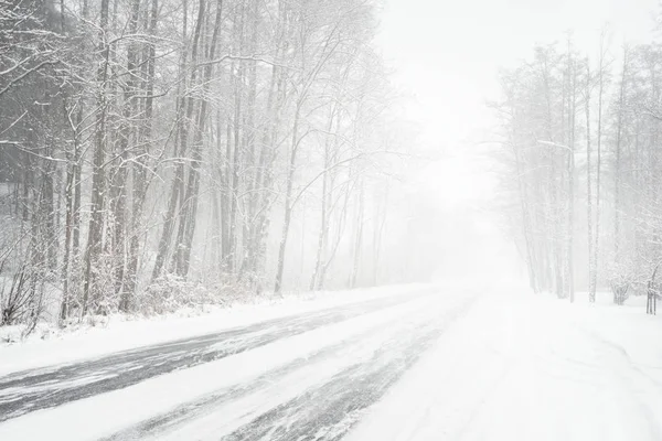 Снежная зимняя дорога во время метели — стоковое фото