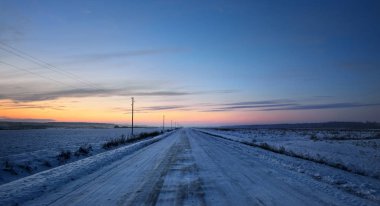 Kışın telgraf direkleri olan kırsal yol 