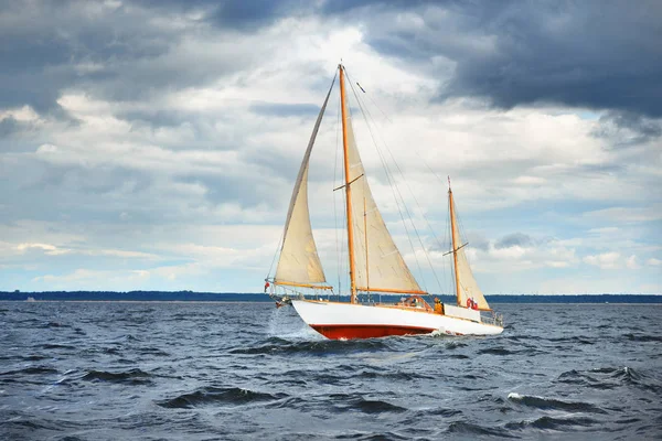 Jachten, zeilen op golven tegen een oever — Stockfoto