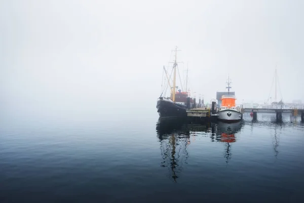 Une jetée avec de petits bateaux sous le brouillard — Photo