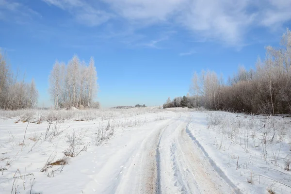 Estrada através do campo coberto de neve russo no inverno — Fotografia de Stock