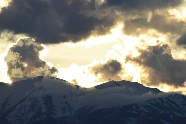 Amazing brilliant winter sunset over mountains with glowing clouds.