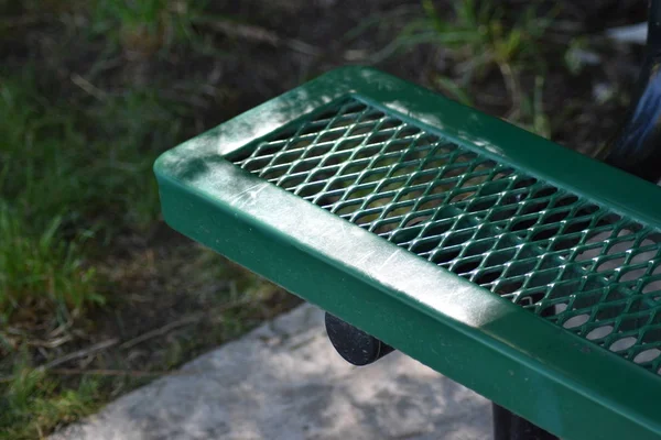 Yeşil park bankı çimento çimento ve yeşil bitki örtüsü üzerine yakın çekim.