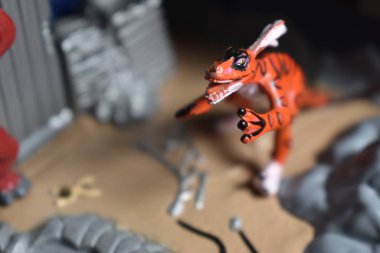 Turuncu Raptor dinozor oyuncağı yıkılan oyuncak kıyamet binalarının üzerinde yürüyor.