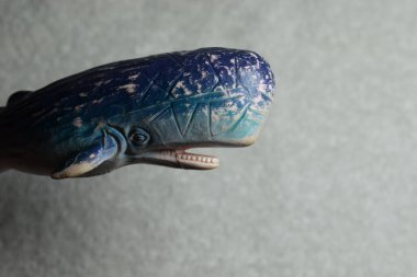 Açık ağızlı, dişli, yüzgeçli ve desenli beyaz arka planı olan mavi oyuncak sperm balinası.. 
