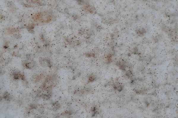 Kahverengi benekli kirli kar ve altında beyaz kar. 