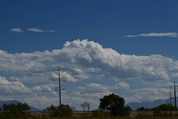 Blauer Himmel Mit Weißen Flauschigen Wolken Telefonmasten Telefondrähten Grünen Bäumen — Stockfoto