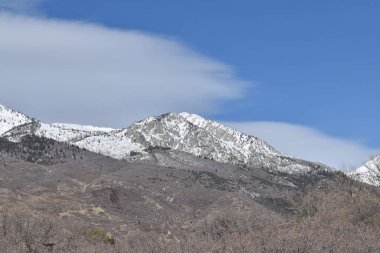 Kahverengi tepeli karlı dağ ve kabarık beyaz bulutlu mavi gökyüzü.. 