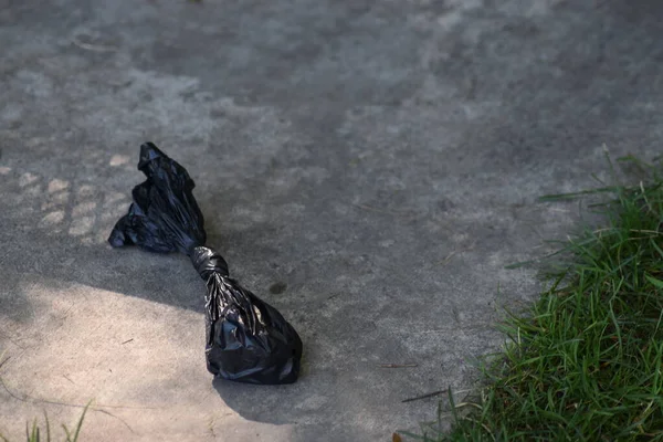 Черный Пластиковый Мешок Мусора Лежащий Цементном Тротуаре Тени Рядом Лужайкой — стоковое фото