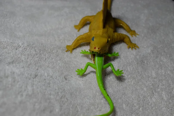 危险的黄色玩具迪米顿恐龙吃着无助的绿色蜥蜴 — 图库照片
