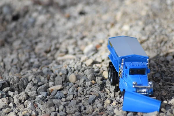 Mavi oyuncak kar küreme kamyonu çakıl zeminde.