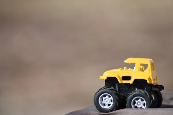 Cool yellow toy truck with awesome big tires on black platform.