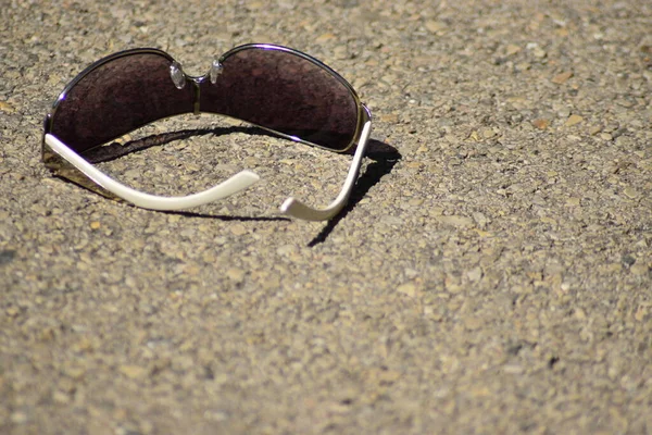 Dunkle Sonnenbrille Mit Weißen Bügelstielen Auf Kiesiger Oberfläche Liegend — Stockfoto