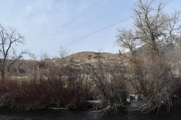 Dunkler Wasserfluss Mit Kahlen Winterzweigen Bäumen Büschen Braunen Hügeln Blauem — Stockfoto