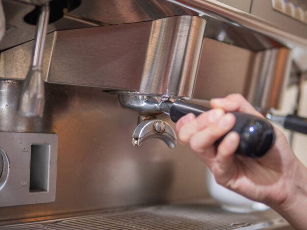 barista putting a portafilter to group head of espresso machine. Barista hand holding portafilter.