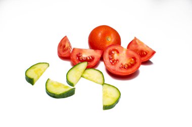 Beyaz arka planda salatalık ve domates. Yeşil salatalık ve kırmızı domates dilimleri yemek için hazırlanıyor. Metin için boşluk