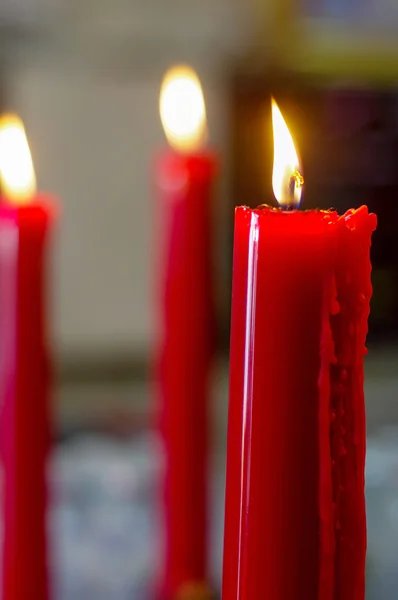 Mnoho rudých pálení, dlouhé svíčky v chrámu budist — Stock fotografie