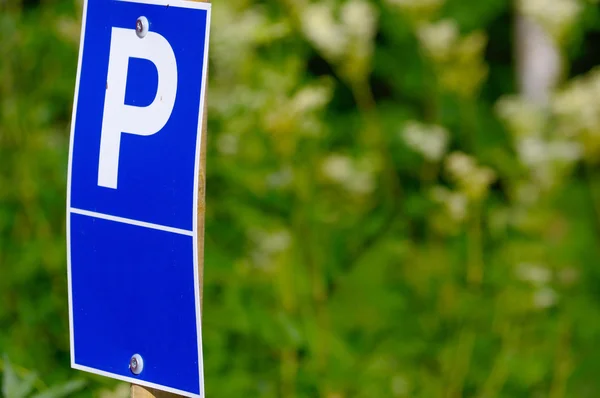 Синій знак паркування з великим P на ньому зелений фон — стокове фото