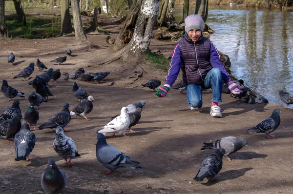 Child playing with doves in the city street. young girl feeding pigeons. — Stockfoto