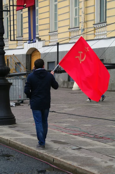 SAINT PETERSBURG, RUSSIA - MAY 09, 2014: lonley man walks with a soviet red flag, hammer and sickle symbols on it. Victory Day celebration. — Stock Photo, Image