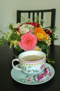 Ahşap arka planda küçük beyaz fincan kahve ve buket çiçekler