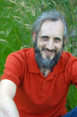 yeşil bir arka planda güneşli gün, potrait oturan sakallı mutlu adam