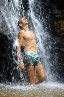 Adam şelale altında rahatlatıcı duş alıyor. Dışarıda