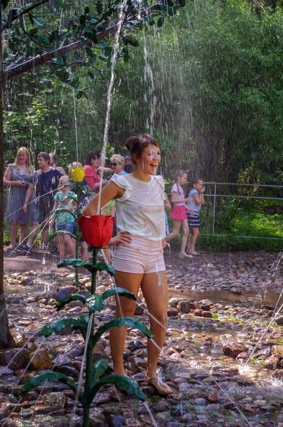 Peterhof, Saint Petersburg, Rusya Federasyonu - 06 Haziran 2014: Mutlu kadın var park su çeşme sıcak yaz gününde oynayan eğlenceli.