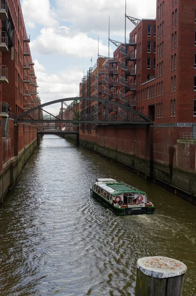 HAMBURG, ALEMANIA - 18 DE JULIO DE 2015: ferry en el canal de casas y puentes históricos Speicherstadt por la noche con vistas panorámicas de los almacenes, famoso lugar río Elba . — Foto de Stock