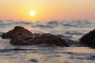dalga deniz ve rock yakın kırmızı turuncu güneş yansıması su ile günbatımı zamanı at. doğa soyut arka plan bulanık. Phuket Island, Tayland